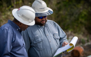 Two men in hard hats looking at a clipboard